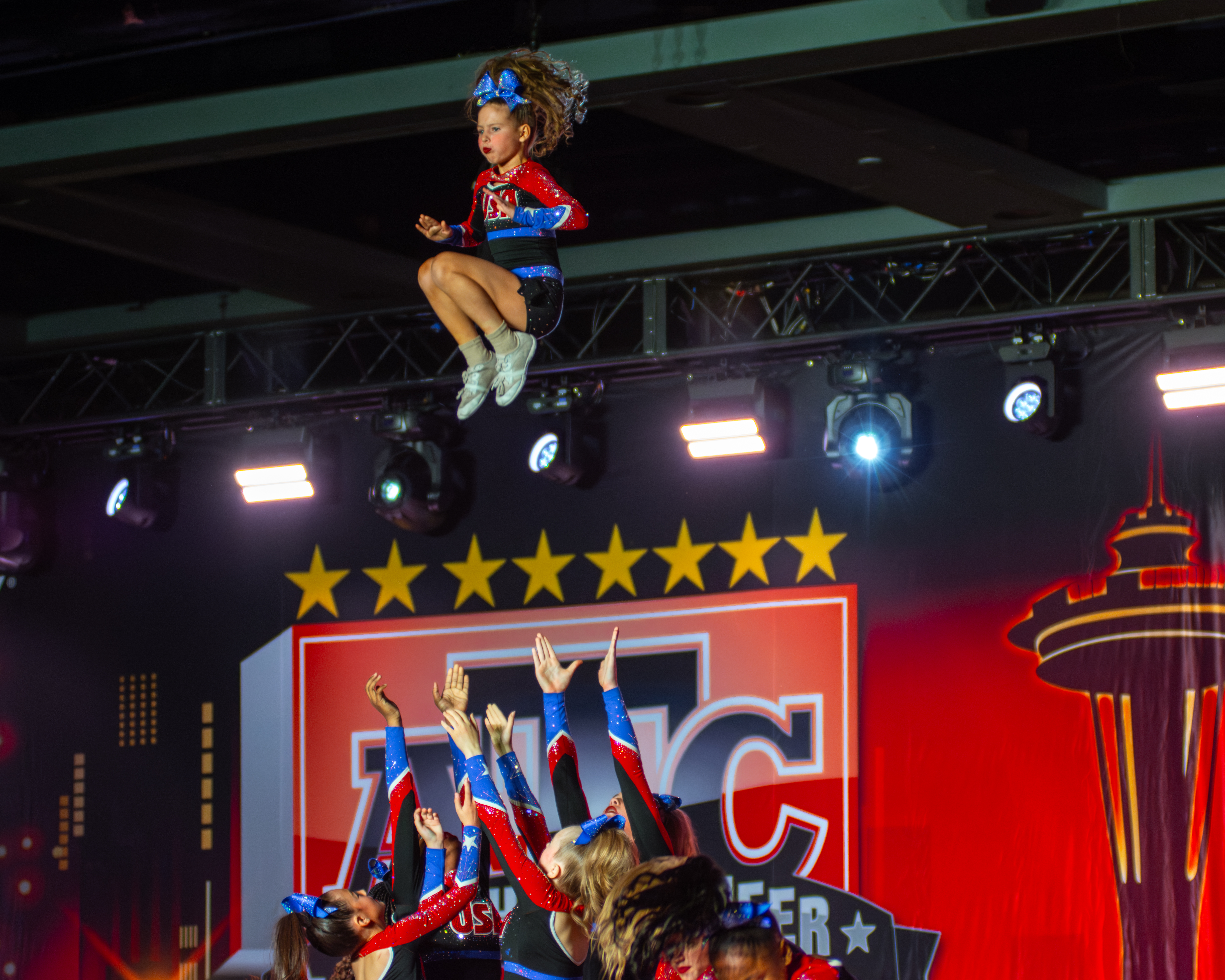 Competitive cheerleader performing airborne stunt at cheer competition - professional cheer photography