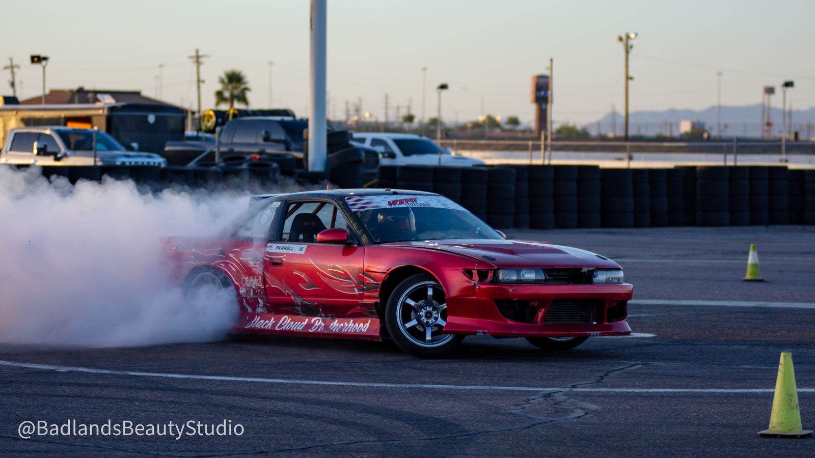 Red drift car sliding sideways with tire smoke at dusk