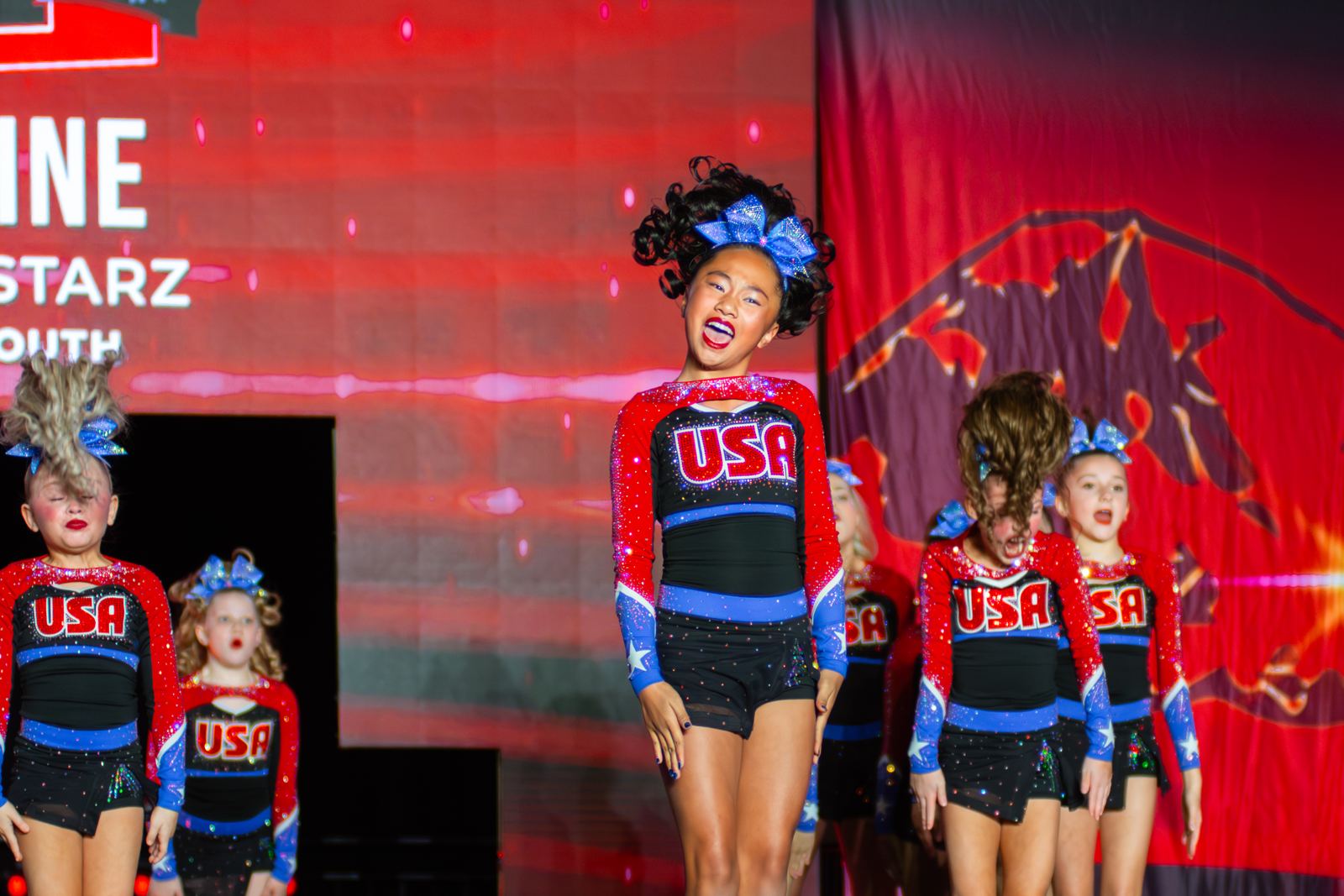 Action photography by Braden Donovan: young cheerleaders performing on a lit stage